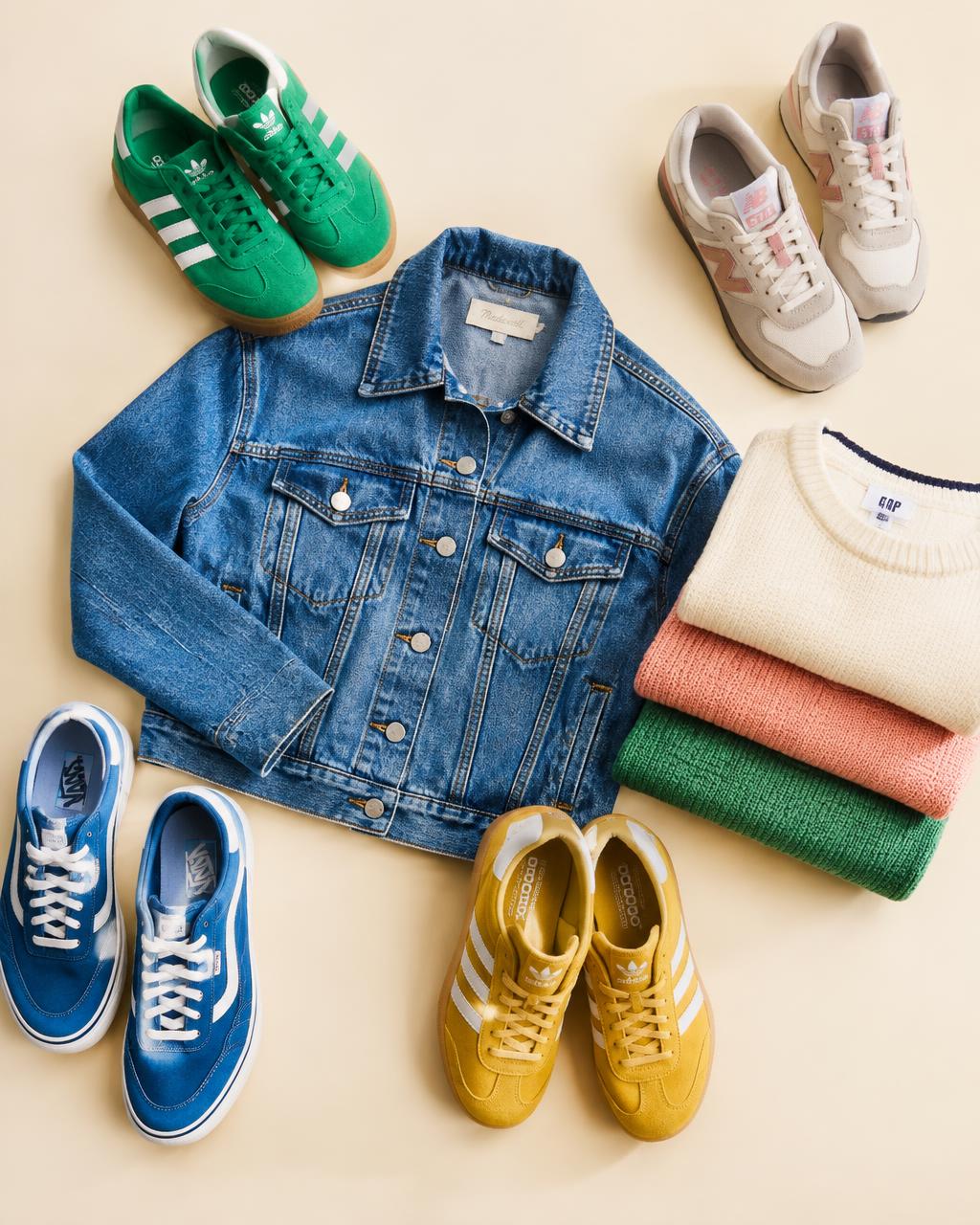 Flat lay of colourful pre-owned sneakers, a denim jacket and folded knitwear